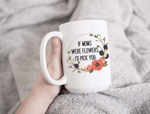 15 oz white ceramic coffee mug slanted back being held by a hand with a grey blanket in the background