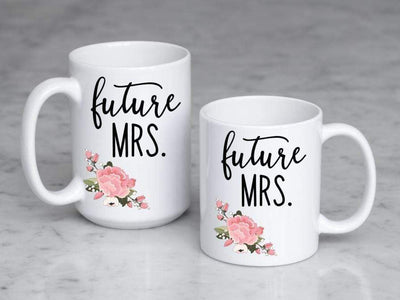 future mrs. in black text with pink and green floral bottom left printed on 11 oz and 15 oz ceramic mugs side by side