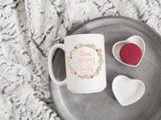 love never fails corinthians 13:8 quote in peach text with peach and olive floral wreath on ceramic mug
